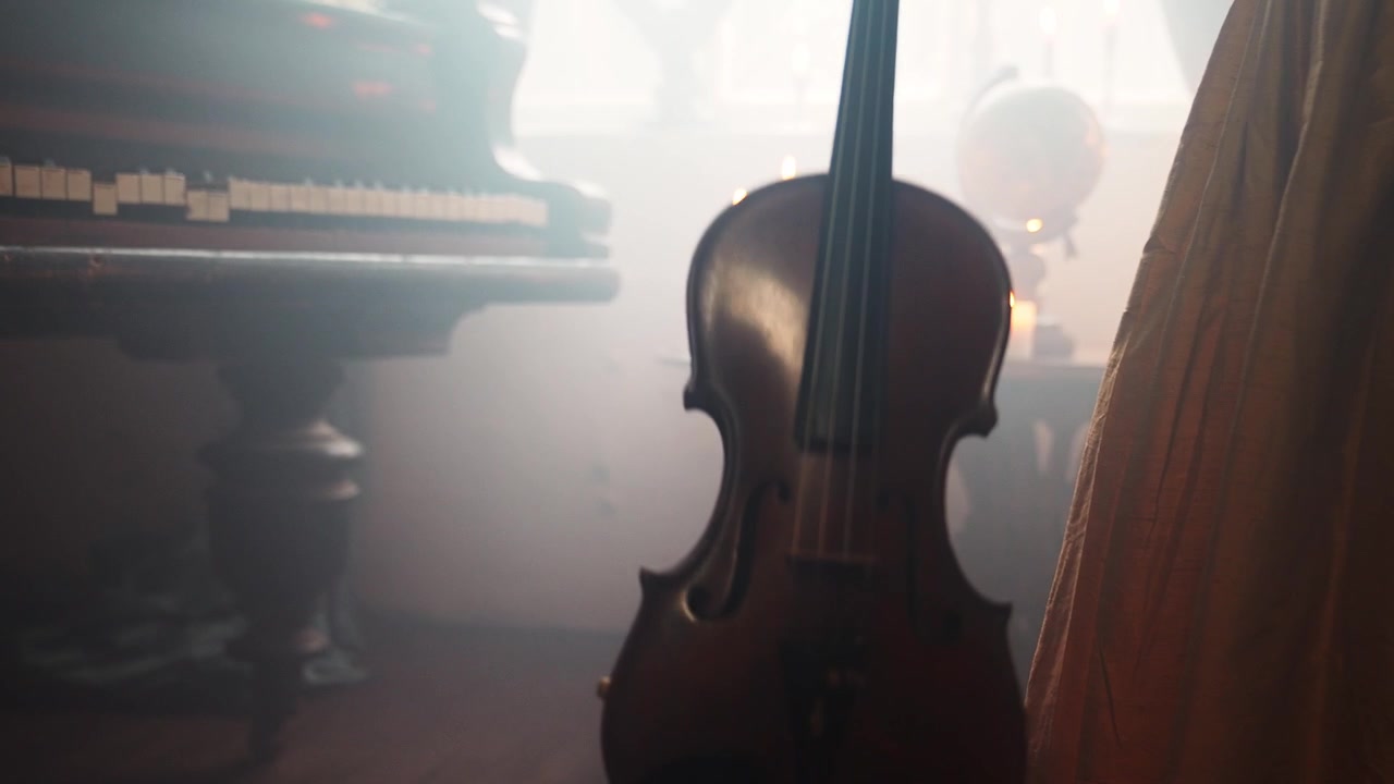 Violino vintage in una stanza buia e suggestiva con pianoforte e candele