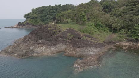 drone orbit shot , birds eye view of granite rock coastline on a tropical island with jungle lush green forest and ocean