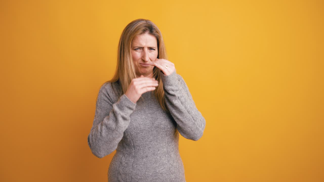 Donna che esprime disgusto e si tappa il naso per un cattivo odore