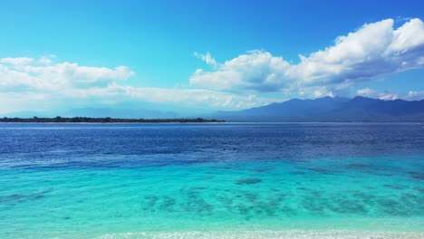 hermosas aguas oceánicas de zafiro en una playa tropical paradisíaca con una vista panorámica de las montañas