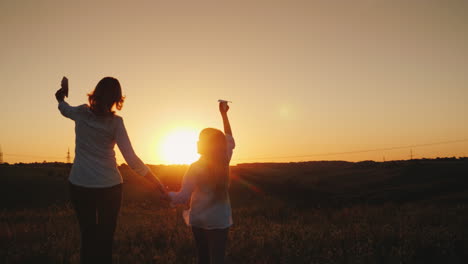 Mutter-Und-Tochter-Spielen-Papierflieger-Bei-Sonnenuntergang-An-Einem-Malerischen-Ort-Glückliche-Zeit-Mit-Dem-Ba