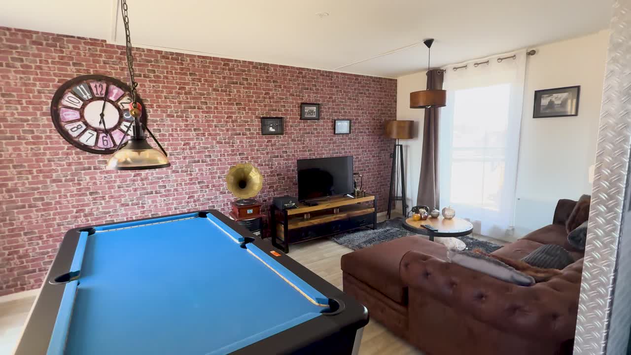 Camera pans through vintage lounge with billiard table, brown sofas, brick wall, and warm light