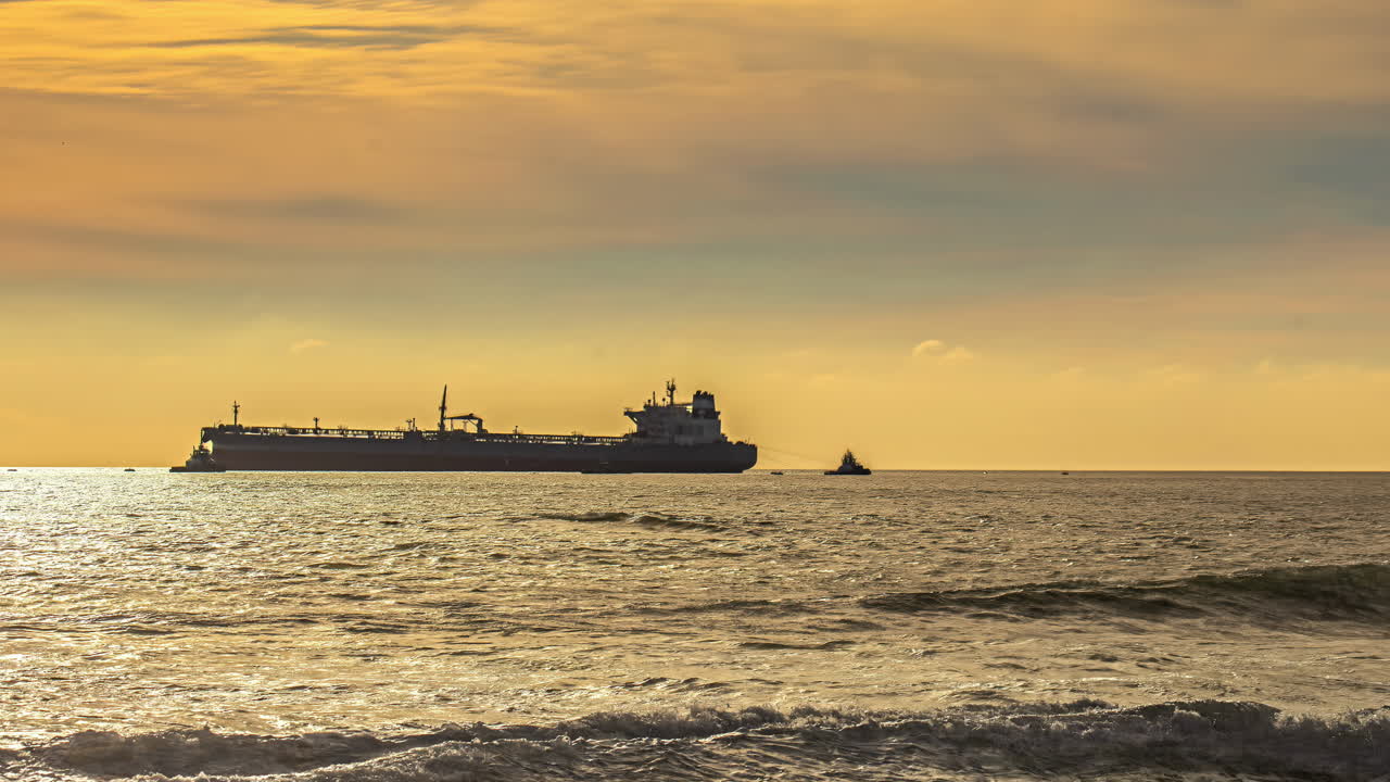 barco de carga masivo amarrado cerca de la costa durante la puesta del sol, vista de lapso de tiempo