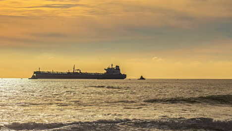 massive cargo vessel moored near coastline during sunset, time lapse view