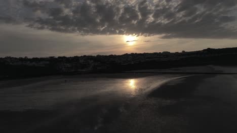 Evening-cloudy-golden-sunset-colours-across-Benllech-beach-silhouette-coastline-Anglesey-aerial-view-ultra-slow-left