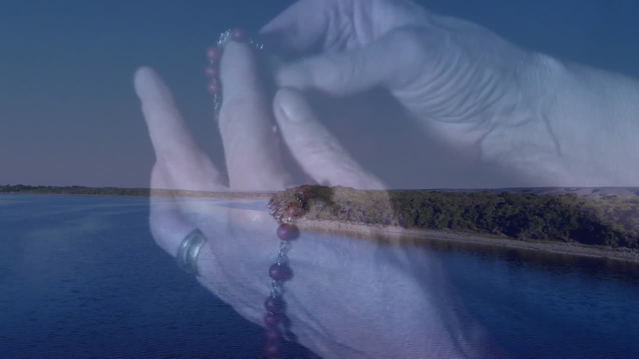 Holding rosary beads over serene lake and forest, person appreciating animation