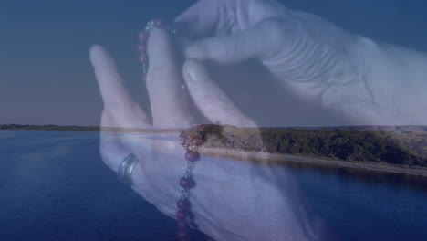 holding rosary beads over serene lake and forest, person appreciating animation