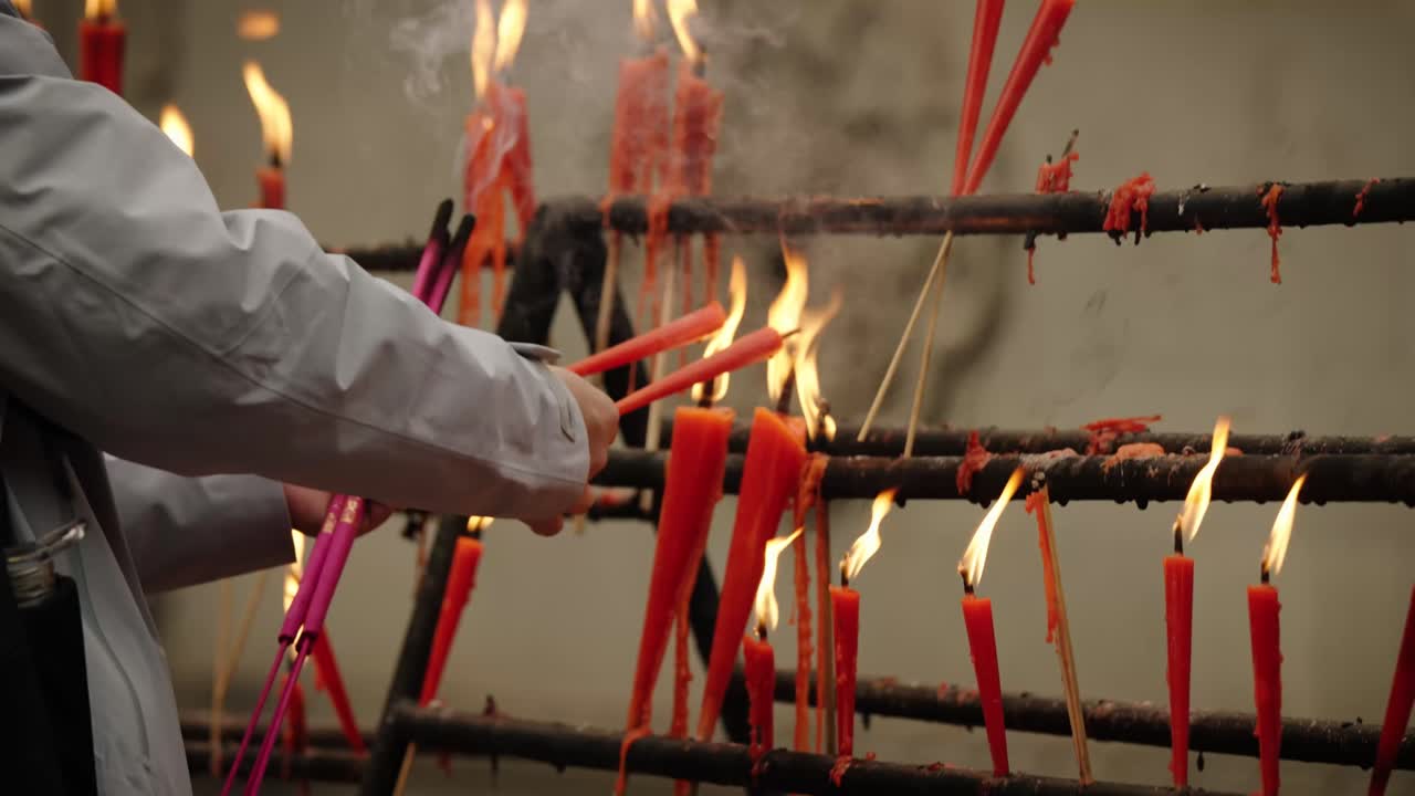 Person lights candles during a Buddhist prayer ritual at Baolun Temple in Chongqing
