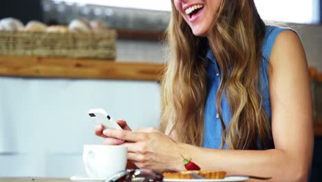 woman text messaging on mobile phone in cafeteria