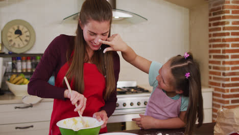 Madre-E-Hija-Caucásicas-Usando-Delantales-Divirtiéndose-Mientras-Hornean-Juntas-En-La-Cocina-De-Casa