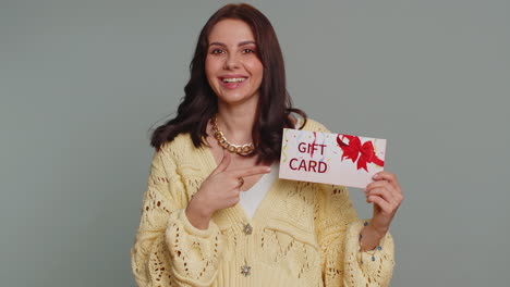 young woman smiling and holding a gift card