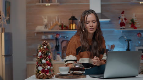 Festive-woman-talking-on-video-call-using-laptop