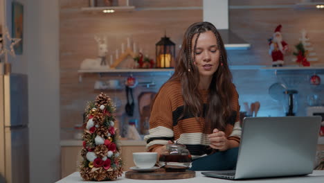festive woman talking on video call using laptop