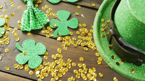 Video-of-st-patrick's-green-hat,-shamrock-and-gold-sequins-on-wooden-background