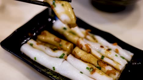 Chopsticks picking up rice noodles in sauce