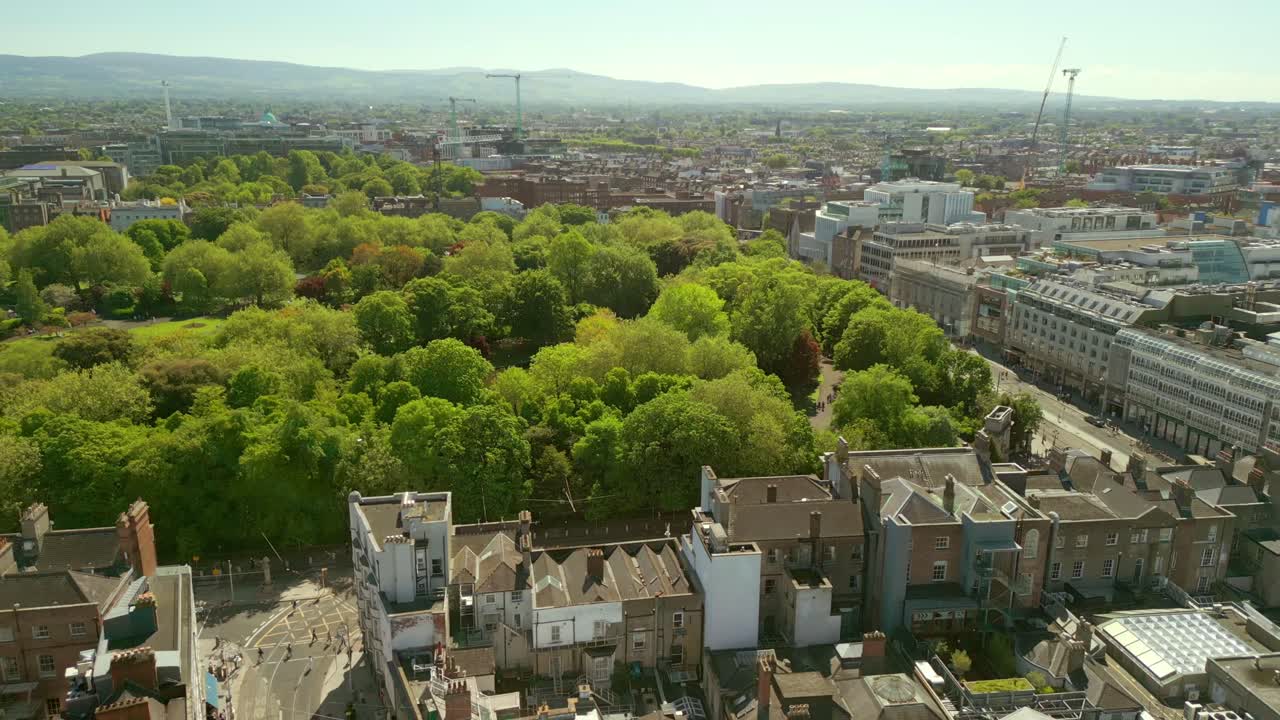 Wide reversing aerial video of St Stephen's Green and the surrounding area in Dublin City Centre, County Leinster, Ireland on a bright sunny day. Filmed in 4K, 60FPS and with Rec709 color.