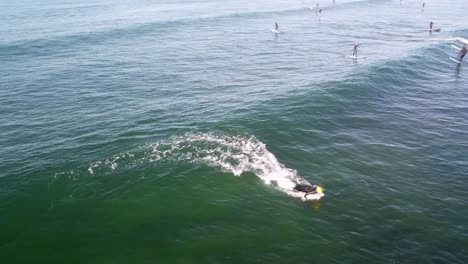 surfer riding a wave with paddleboarders in the background