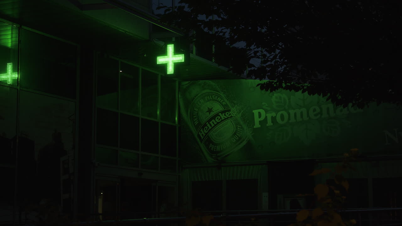 A pharmacy advertising board and a Heineken advertising board complement each other.