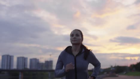 mujer deportiva con capucha corriendo en la ciudad mientras entrena al aire libre temprano en la mañana 1