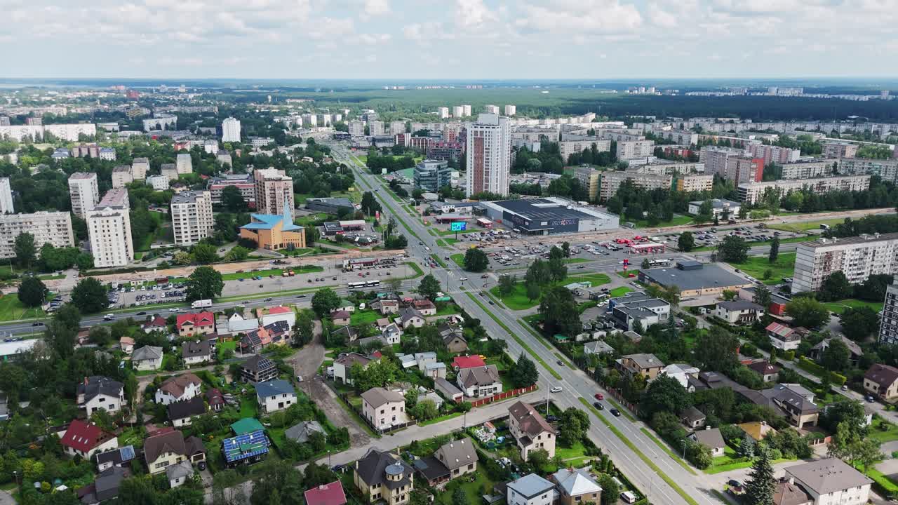 Paesaggio urbano vivace che mostra i condomini del quartiere Darzciems e una strada principale che lo attraversa.