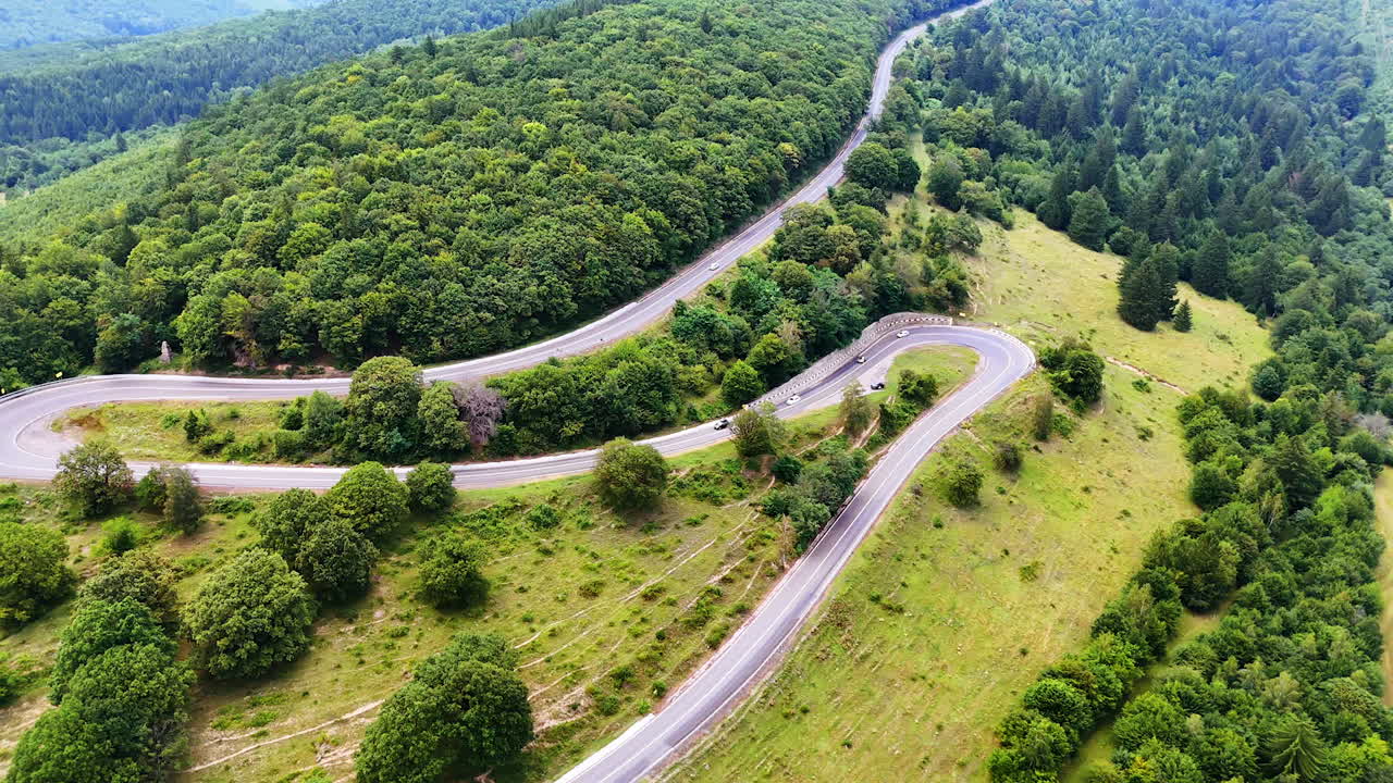 Winding road through lush green hills. A scenic road curves through dense green hills, surrounded by trees and natural beauty during daylight hours