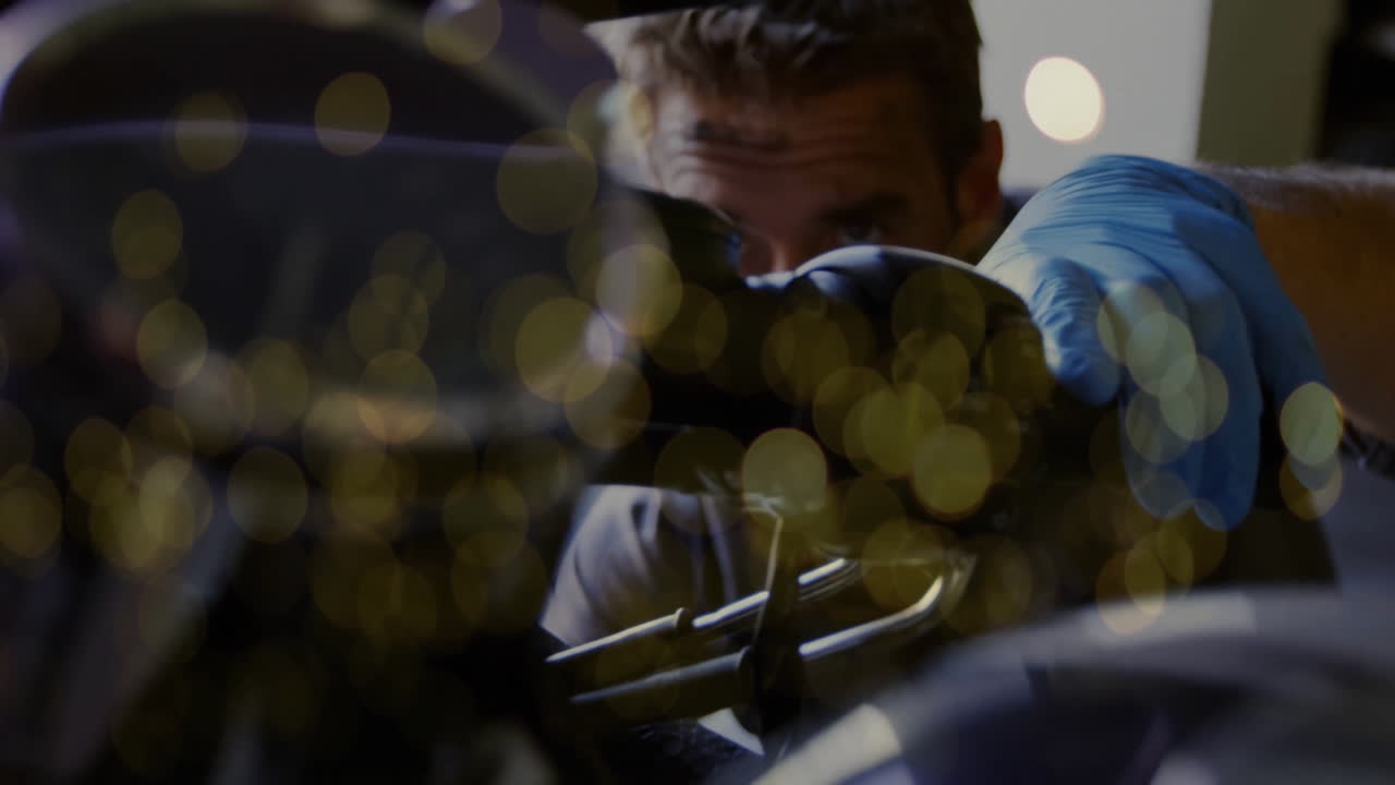 Mechanic wearing blue glove showing animated overlay on engine in auto workshop, with golden bokeh