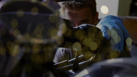 mechanic wearing blue glove showing animated overlay on engine in auto workshop, with golden bokeh