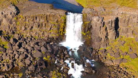 Toma-Lenta-De-Una-Cascada-Que-Fluye-Sobre-Un-Acantilado-En-El-Vasto-Campo-Islandés