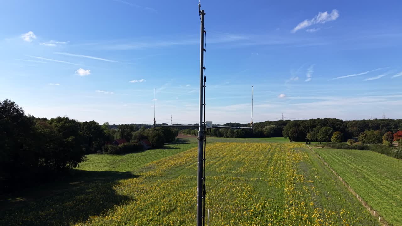 Aerial orbit of radio tower sending signals on sunny summer day in America. Yellow sunflower field and forest trees