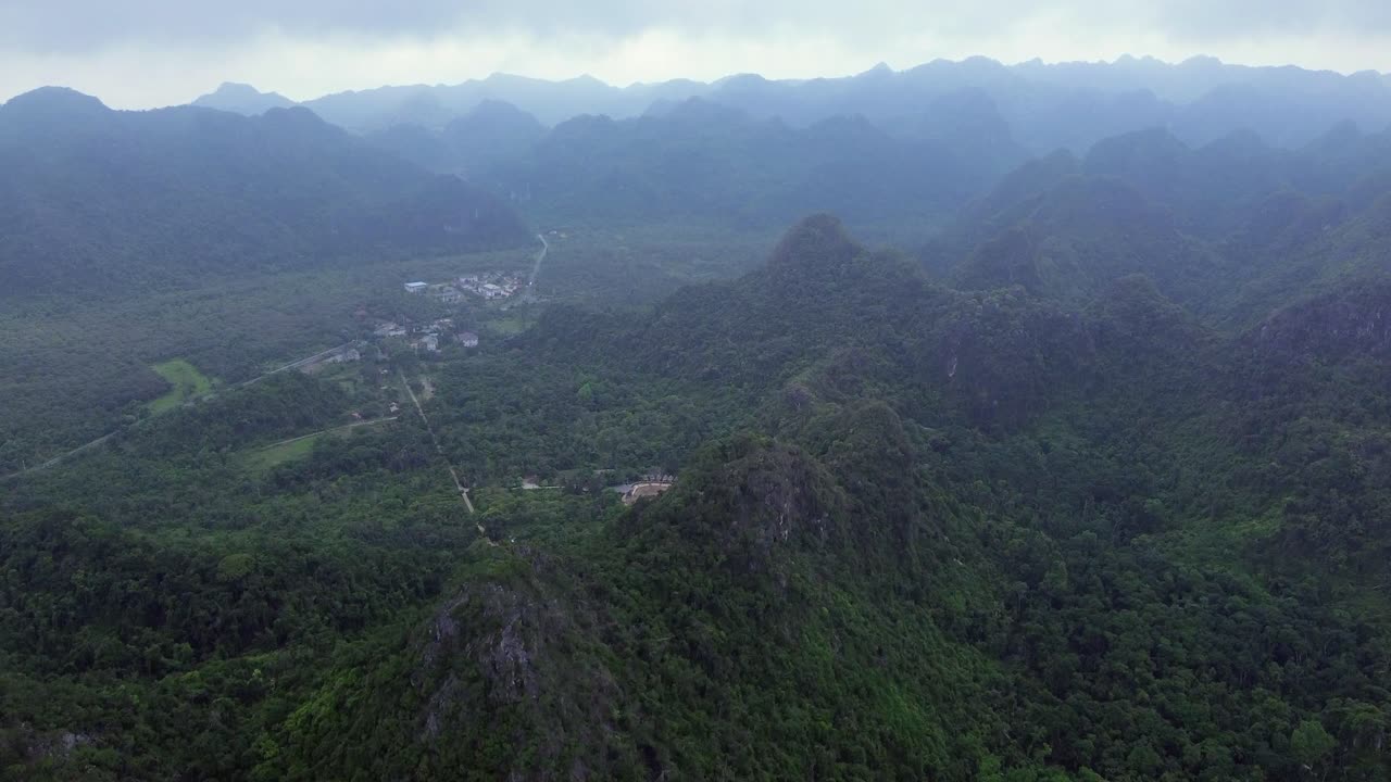 Zoom in drone shot of rocky coast and emerald water in Cat Ba Island on a bright day