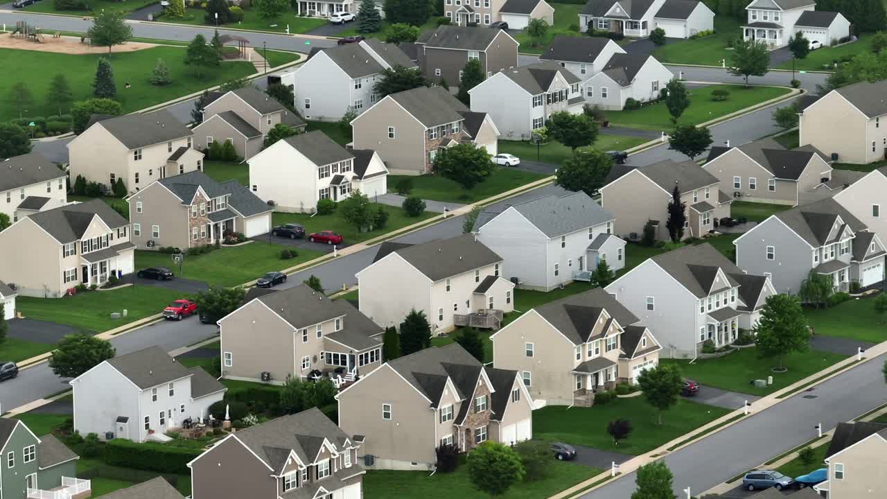 New Upper Class Real Estate Houses in American Suburb. Noble Residential Area at sunny day in USA. Luxury Suburb of Small American Town. White facade and grey roofs with green yards in spring.