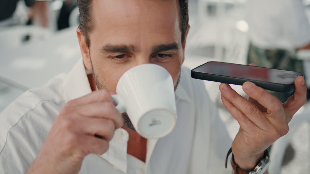 hombre escuchando audio usando teléfono en un café de primer plano. ejecutivo bebiendo café