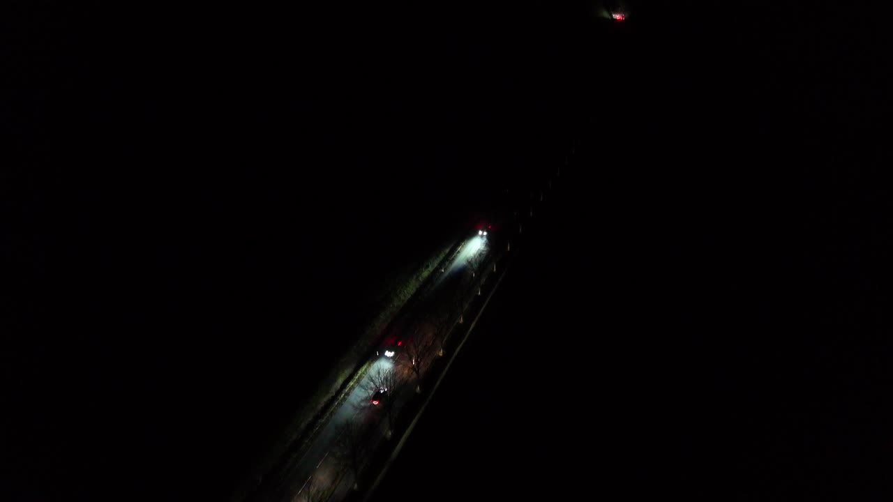 Driving cars on dark suburb intersection road of USA. Lighting headlights of vehicles on rural highway. Aerial top down shot.