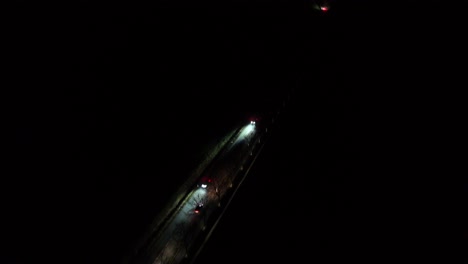 driving cars on dark suburb intersection road of usa. lighting headlights of vehicles on rural highway. aerial top down shot.
