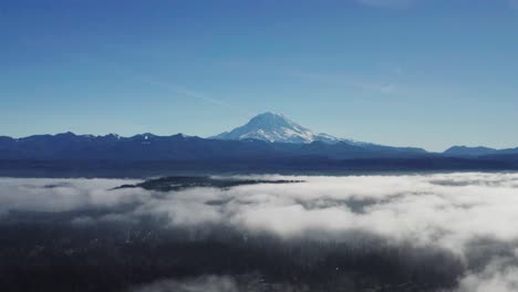 Aerial-View-Of-Famous-Mount-Rainier-With-Clouds-Over-Green-Forest-In-Washington-State,-USA