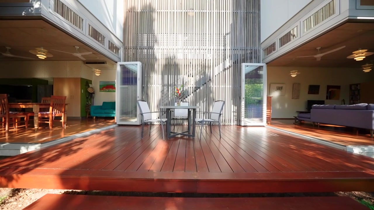 Patio tropicale in stile industriale di una villetta a schiera con mobili da esterno e vegetazione lussureggiante