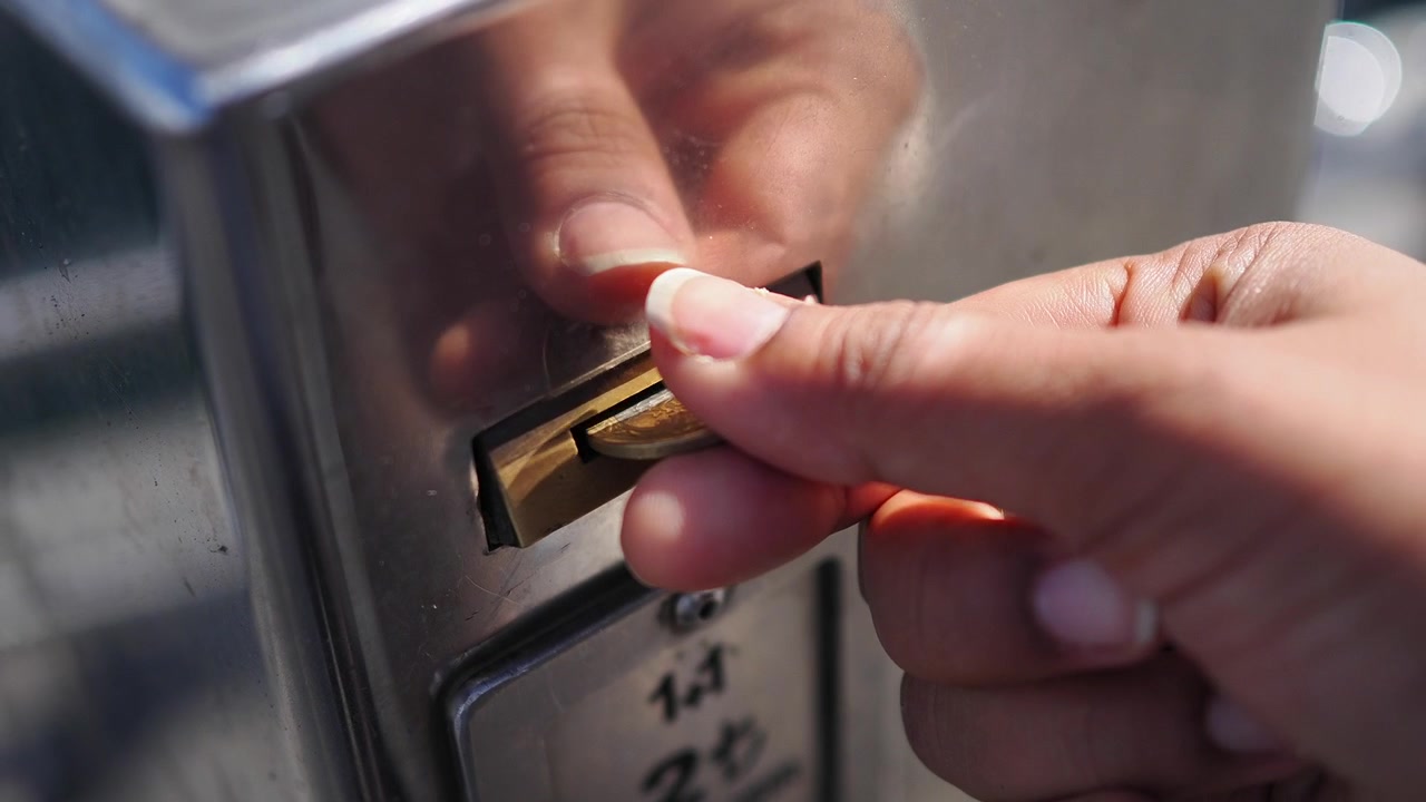 Hand Inserting Coin into Metal Vending Machine Slot