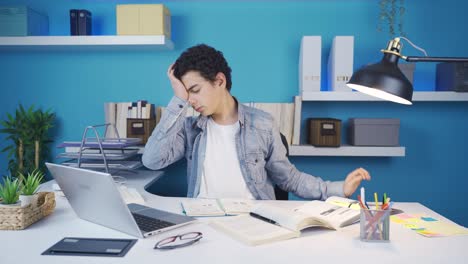 the young man gets bored of studying a lot and starts to fall asleep at his desk.