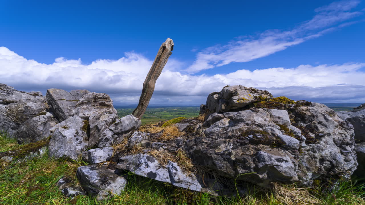 Timelapse di paesaggio rurale con formazione rocciosa e pilastri di legno in primo piano e colline in lontananza durante una giornata nuvolosa e soleggiata visto da Carrowkeel nella contea di Sligo in Irlanda