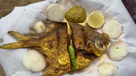 Fried-white-pomfret-served-in-the-beach-of-Digha,-Bengal,-India-with-onion-and-lime