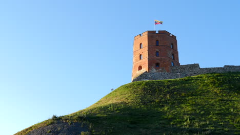 gediminas castle hilltop fortification tower in vilnius, flying lithuanian flag under blue sky