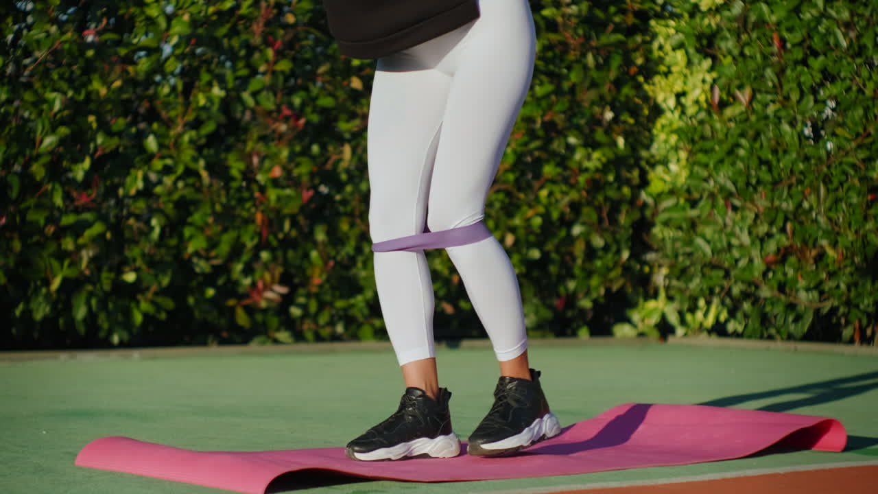 여성이 야외에서 저항 밴드로 다리 운동을 하고 있습니다.