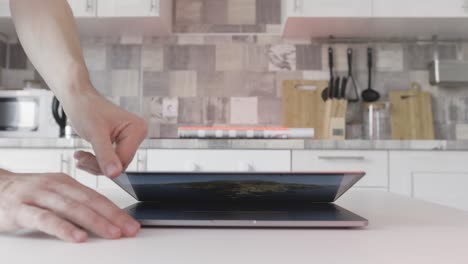 person opening a laptop in a kitchen