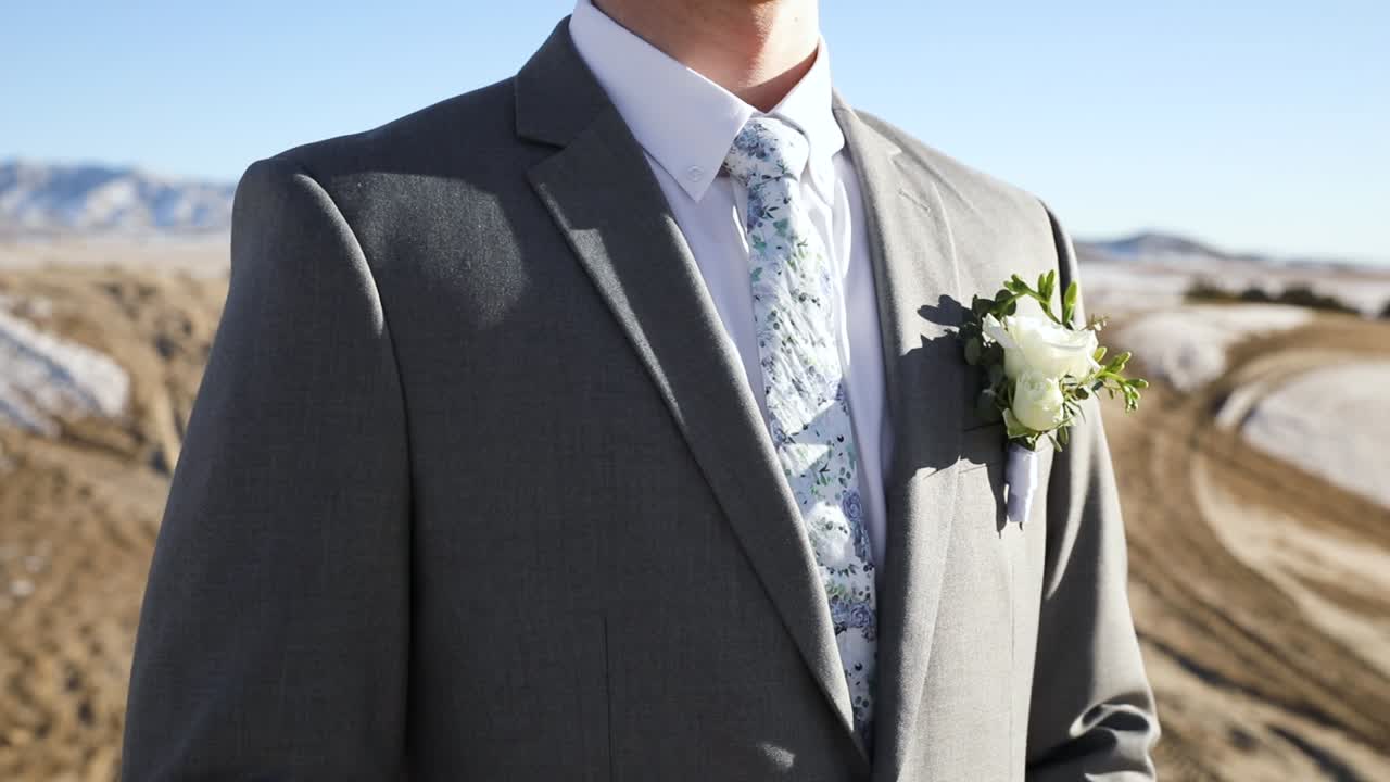 concepto de boda - novio guapo con chaqueta de traje, corbata y ramillete floral