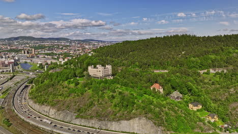 Oslo-Norway-v18-drone-flyover-hillside-kongshavn-high-school,-reveals-sørengautstikkeren-neighborhood-with-apartment-complex-on-the-peninsula-with-waterfront-view---Shot-with-Mavic-3-Cine---June-2022