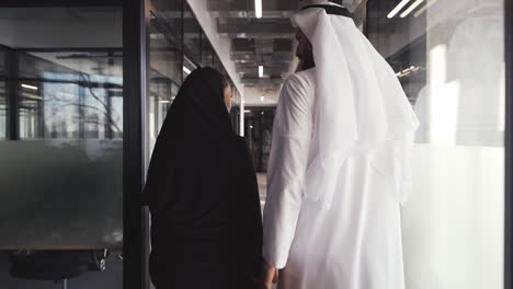 handsome man and woman with traditional clothes working in an office of dubai