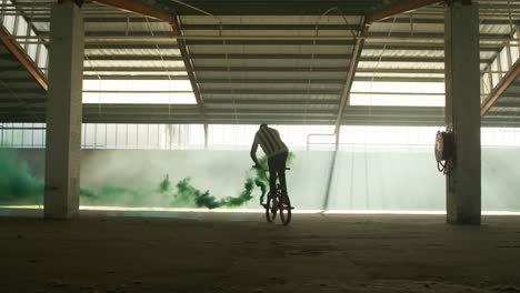 bmx rider in an empty warehouse using smoke grenade