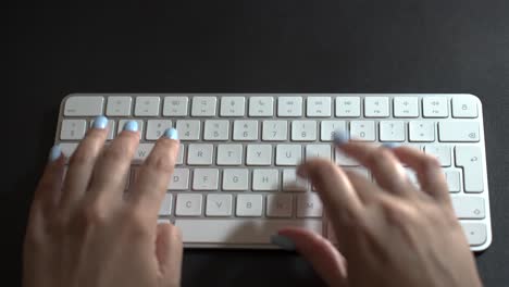 Person-typing-on-white-computer-keyboard,-top-view