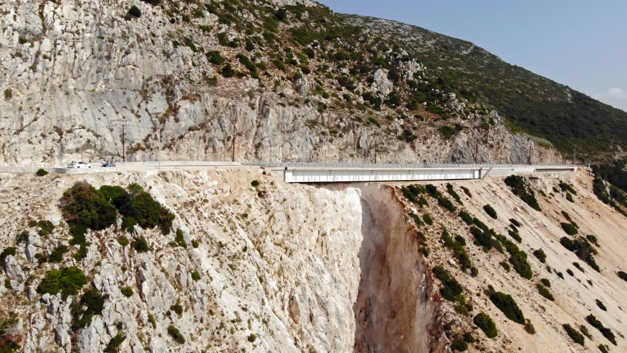 туристы на пляже миртос смотрят на вершину горы со скалистым утесом и пышной растительностью в кефалонии, греция