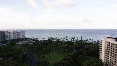 drone shot flying over waikiki's dense shoreline all the way to the water